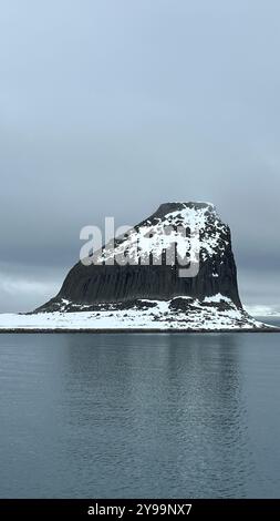 Una suggestiva vista della roccia di Edimburgo nell'Oceano meridionale, Antartide, con la sua vetta innevata che si innalza sopra le acque calme Foto Stock