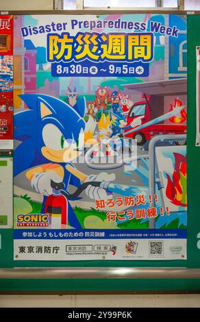 tokyo, giappone - 24 settembre 2024: Poster giapponese illustrato fissato su un muro della stazione ferroviaria per la settimana di preparazione al disastro con sega, un videogioco Charac Foto Stock