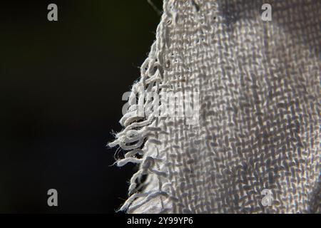 Un pezzo di tessuto con bordi sfilacciati. I bordi sfilacciati conferiscono al tessuto un aspetto usurato e lacerato Foto Stock