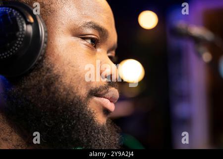 Produttore musicale di talento che modifica file audio con console e apparecchiature stereo, tecniche di mixaggio e masterizzazione nel suo studio di casa. Il compositore artista maschile lavora alla creazione di colonne sonore. Primo piano. Foto Stock