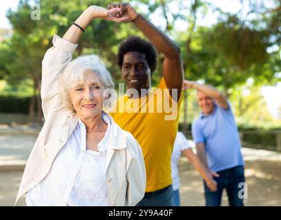 Hanno lasciato persone diverse anziane e di mezza età godendo danze latine che si rompono in coppie sulla zona sabbiosa tra gli alberi Foto Stock