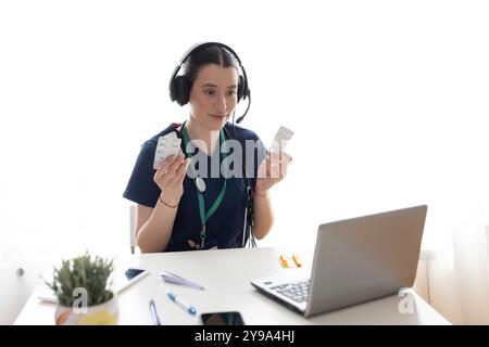 Medico donna che utilizza le cuffie durante le videochiamate e attraverso il computer portatile in ufficio Foto Stock