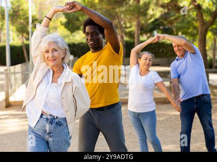 Felici i pensionati multinazionali maturi che trascorrono il tempo insieme e ballano in coppia all'aperto Foto Stock