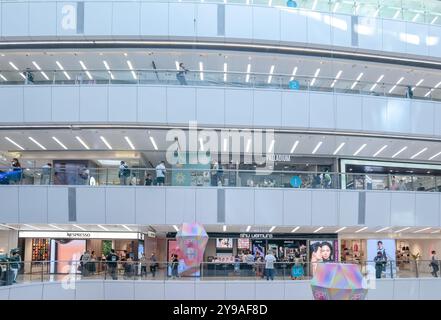 Hong Kong, Cina, 8 ottobre 2024: Un moderno centro commerciale di Hong Kong con interni piastrellati bianchi e scale mobili che portano ad un livello superiore. Foto Stock