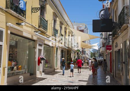 Vivace via dello shopping con negozi, gente e tende da sole in stile mediterraneo, zona pedonale, centro storico, Faro, Algarve, Portogallo, Europa Foto Stock