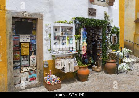 Piccolo negozio in un vicolo acciottolato che offre souvenir e artigianato colorato, R. Direita, Obidos, Obidos, Oeste, centro, Estremadura, Portogallo, Europa Foto Stock