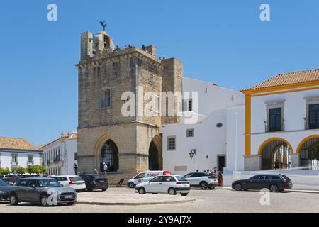 Chiesa storica con campanile, circondata da automobili ed edifici bianchi, con il sole, se Catedral de Faro, Cattedrale di Faro, largo da se, Faro Foto Stock