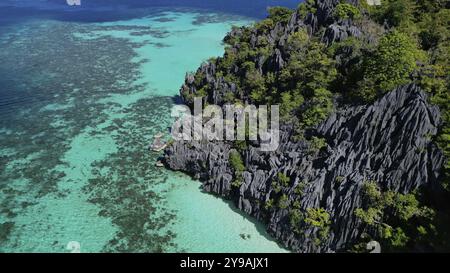 Vista aerea dell'isola tropicale delle Filippine. Spiaggia di sabbia bianca, scogliere, montagne con baia blu e splendida barriera corallina Foto Stock