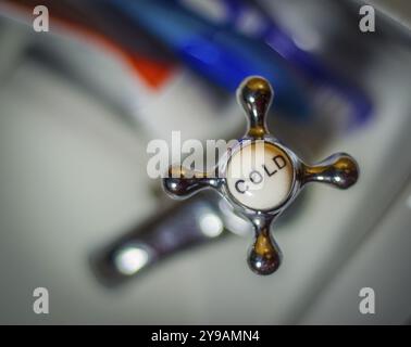 Dettagli di Un rubinetto a freddo vintage e spazzolini da denti su Un lavabo Foto Stock