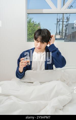 Un uomo di vent'anni che si alza brevemente e beve acqua Foto Stock