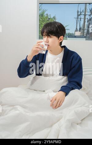 Un uomo di vent'anni che si alza brevemente e beve acqua Foto Stock