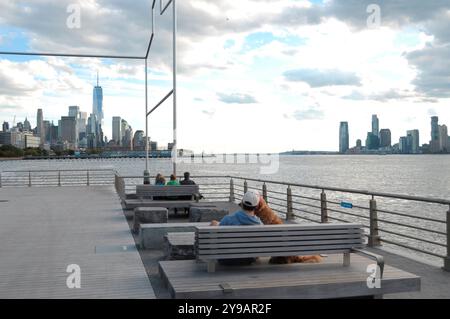 New York, Stati Uniti. 8 ottobre 2024. Le persone sono viste a Gansevoort Beach a Manhattan, New York City, mentre la vista del centro di Manhattan e di Jersey City si vede sullo sfondo. Credito: SOPA Images Limited/Alamy Live News Foto Stock