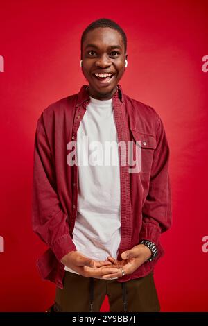 ritratto di un giovane afroamericano con cuffie su sfondo rosso isolato, foto verticale Foto Stock