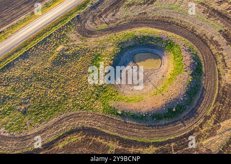 Veduta aerea dei binari della mietitrice intorno a una diga di essiccazione su terreni agricoli a Moolort nel Victoria centrale, Australia Foto Stock