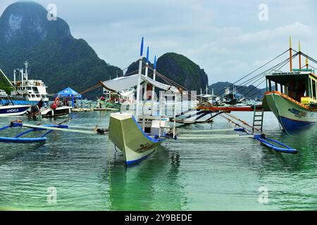 Vista ravvicinata delle tradizionali barche in legno e bambù, Bangkas attraccate sul porto. El Nido, Palawan, Filippine Foto Stock