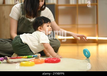 Amata giovane madre e simpatico bambino che gioca con un giocattolo didattico nel soggiorno Foto Stock