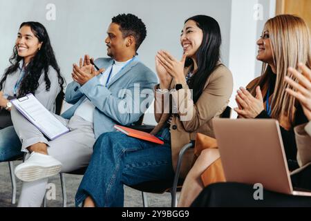 Diversi gruppi di colleghi che battono e sorridono durante una riunione di lavoro in un ufficio, favorendo il lavoro di squadra e la motivazione. Foto Stock