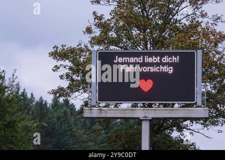 Jemand liebt Dich Fahr vorsichtig. Seit April schmücken 17 digitale Verkehrstafeln in Köln zeitweise humorvolle Sprüche auf Kölsch. Diese Botschaften, die normalerweise für Verkehrsinfos genutzt werden, erscheinen nur, wenn keine Staus oder Gefahren gemeldet werden müssen. Insgesamt werden drei verschiedene kölsche Nachrichten für die Autofahrerinnen und Autofahrer angezeigt. *** Qualcuno ti ama guidare con attenzione. Da aprile, 17 segnali stradali digitali a Colonia sono stati temporaneamente adornati con canti umoristici a Kölsch. Questi messaggi, che vengono normalmente utilizzati solo per le informazioni sul traffico Foto Stock