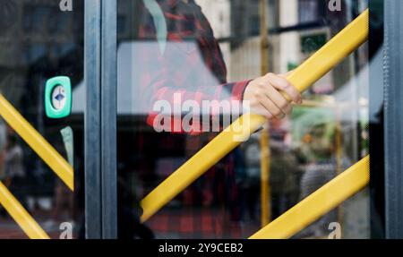 la ragazza sta vicino alla porta dell'autobus e si tiene al corrimano. sicurezza stradale nei trasporti pubblici Foto Stock