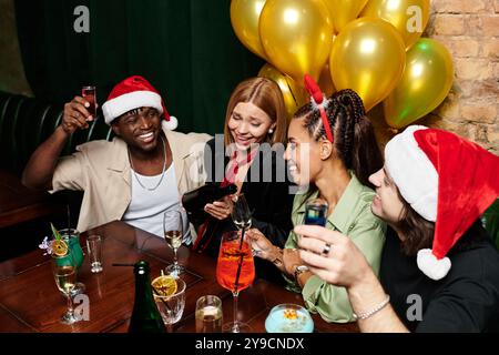 I colleghi si godono una serata vivace a una festa di vacanza, condividendo risate e bevande festive. Foto Stock