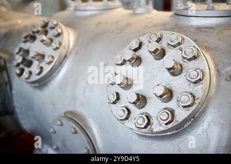 Due coperchi in metallo a vapore o botole piastra delle valvole del compressore in primo piano verniciata con vernice grigia imbullonata con viti prigioniere e dadi fondo con copyspace Foto Stock