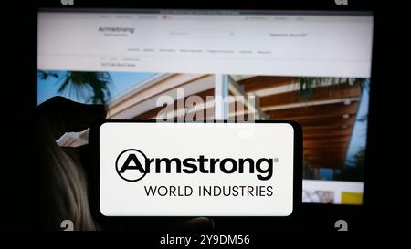 Persona che detiene un cellulare con il logo della società statunitense Armstrong World Industries Inc. Sullo schermo di fronte alla pagina Web aziendale. Mettere a fuoco il display del telefono. Foto Stock