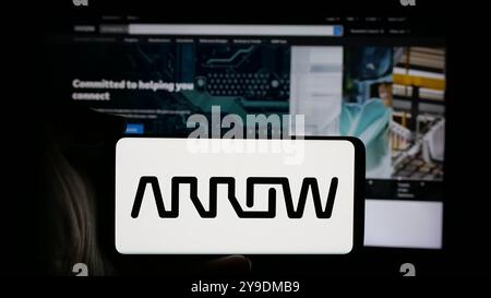 Persona che detiene un cellulare con il logo della società statunitense Arrow Electronics Inc. Sullo schermo di fronte alla pagina Web aziendale. Mettere a fuoco il display del telefono. Foto Stock
