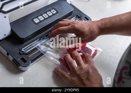 Uomo che utilizza la macchina di tenuta sottovuoto per l'imballaggio sottovuoto della paprika in sacchetti di plastica. . Foto di alta qualità Foto Stock