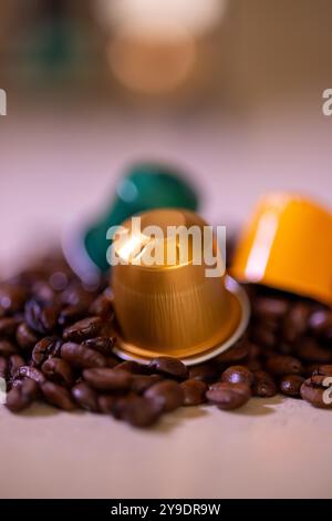 Un primo piano dettagliato che mostra capsule colorate che poggiano sui chicchi di caffè. L'immagine cattura varietà e consistenza nei moderni prodotti a base di caffè Foto Stock