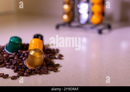 Capsule di caffè luminose sopra chicchi di caffè scuri con un moderno sistema di gestione delle capsule sullo sfondo. Uno shot perfetto per gli amanti del caffè e per l'enthusia delle capsule Foto Stock