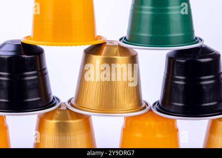 Una vivace piramide di capsule di caffè in vari colori si distingue su uno sfondo bianco pulito Foto Stock
