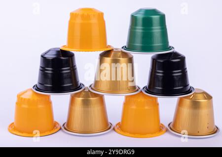 Una disposizione sorprendente di capsule di caffè colorate forma una piramide su uno sfondo bianco incontaminato, perfetto per gli amanti del caffè Foto Stock