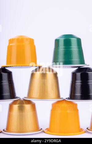 Una piramide artistica di capsule di caffè in colori assortiti si apre sullo sfondo bianco, ideale per mettere in risalto i prodotti del caffè Foto Stock