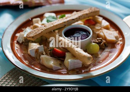 Squisito vassoio di formaggi gourmet con frutta fresca e bastoncini di pane artigianali. Foto Stock