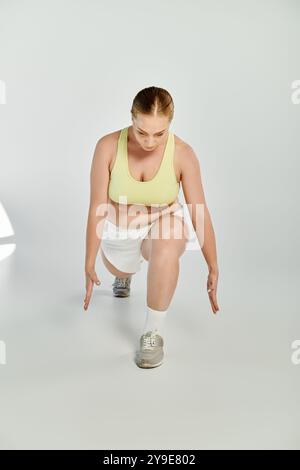 Una donna sportiva dedicata si esercita con gli affondi in uno studio vivace, mostrando la sua attenzione e il suo impegno. Foto Stock