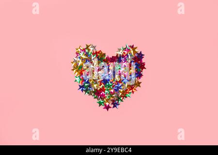 Un cuore realizzato con stelle colorate su sfondo rosa con spazio di copia Foto Stock