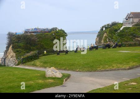 Persone sedute vicino al Footbridge per "The Island" (Towan Island) su Towan Beach a Newquay Bay dal Southwest Coastal Path, North Cornwall, Inghilterra Foto Stock