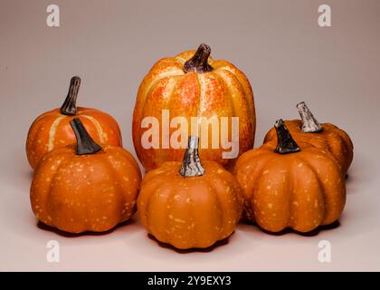 Gruppo di piccole decorazioni di zucche artificiali su sfondo luminoso, carta da parati autunnali, stagione delle zucche, sfondo autunnale, ringraziamento, halloween Foto Stock