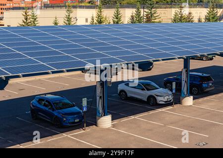 Duluth, Minnesota, Stati Uniti - 15 settembre 2024: Ricarica di auto elettriche nel parcheggio sotto i pannelli solari. Foto Stock