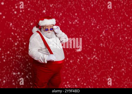 Foto di fresco uomo in sovrappeso grave take off retro specifiche indossare babbo Natale cappello costume isolato colore rosso sfondo Foto Stock