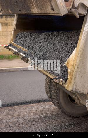 Un team di operai che gestiscono macchinari pesanti per ripavimentare una strada residenziale nel Wiltshire. Foto Stock