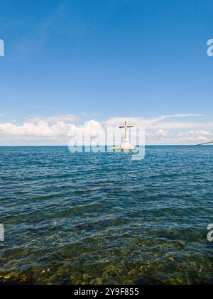 Grande croce in mezzo al mare. Cimitero sommerso sull'isola Camiguin. Filippine. Foto Stock