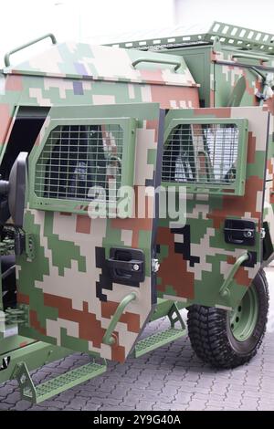 Primo piano dettagliato di un moderno veicolo militare con camouflage pixelato e griglie protettive. Foto Stock