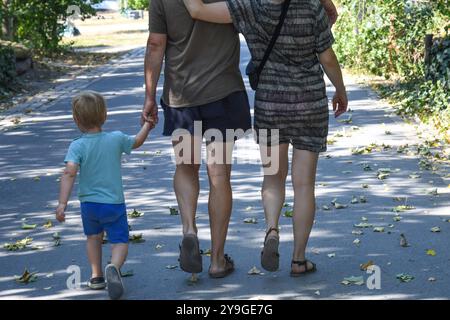 Familienausflug- Eltern mit kind an der hand gehen in einem Park a Berlin spazieren. *** Gita di famiglia genitori con un bambino per mano andare a fare una passeggiata in un parco a Berlino Foto Stock