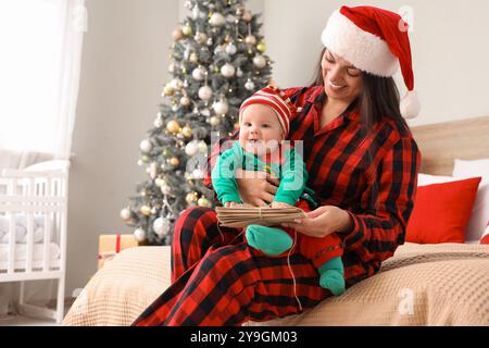 Madre con lettere a Babbo Natale e il suo bambino vestito da elfo in camera da letto la vigilia di Natale Foto Stock