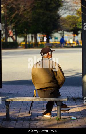 Vita quotidiana in Giappone un uomo anziano che si rilassa su una panchina del parco nel dopoguerra Foto Stock