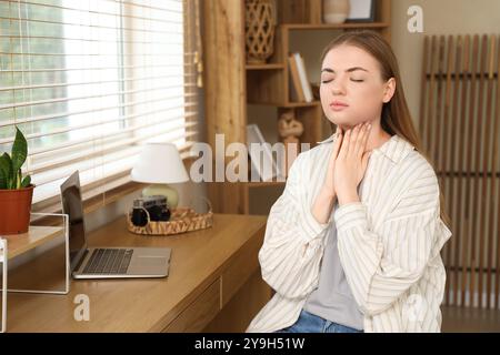 Giovane donna che si autoesamina la ghiandola tiroidea a casa Foto Stock