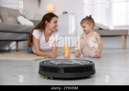 La madre trascorre del tempo con la figlia in camera e si concentra sull'aspirapolvere robotizzato Foto Stock