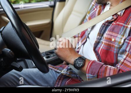 Uomo che fissa il sedile di sicurezza all'interno dell'auto, primo piano Foto Stock