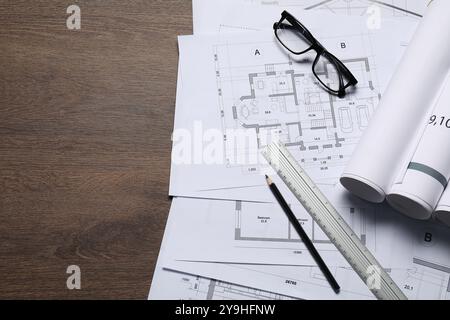 Diversi disegni architettonici, vetri, righello e matita su tavolo in legno, vista dall'alto. Spazio per il testo Foto Stock